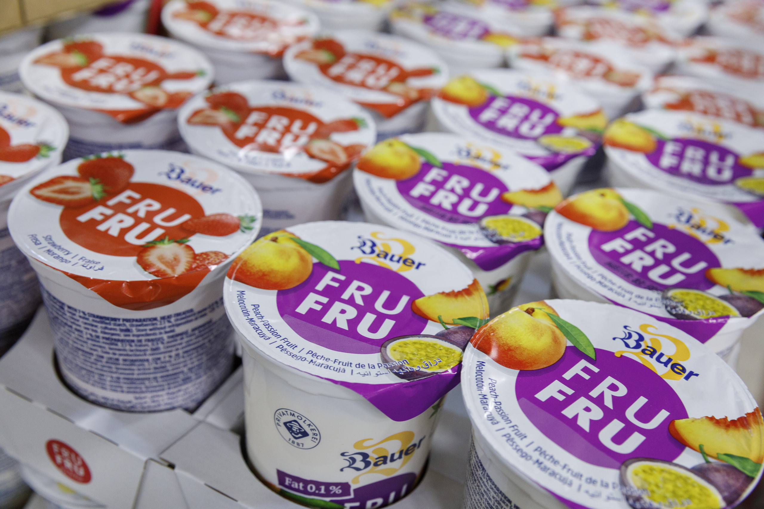 <p>Man sieht: Nahaufnahme verschiedener Bauer Joghurtbecher der Sorte „FRU FRU“ (Erdbeere und Pfirsich-Maracuja). Die effiziente Endverpackung und Palettierung dieser Produkte wird in der Privatmolkerei Bauer durch moderne Cobot-Technologie von Yaskawa sichergestellt.<p>