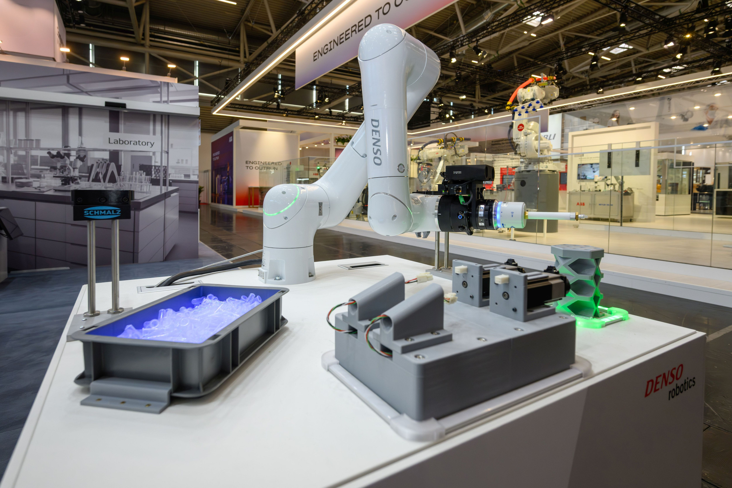 Der kollaborative Roboter Cobotta Pro steht auf einem Messestand, daneben steht eine Box mit Objekten.