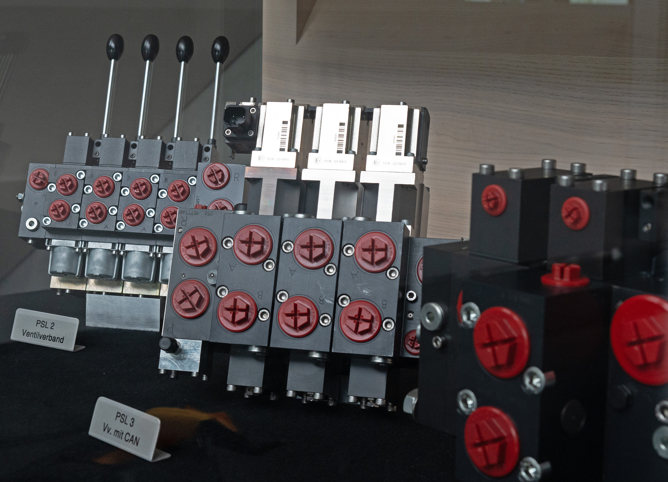 <p>Zu sehen ist ein Hawe‑Hydraulik‑Ventilverband (Ventilblock) mit mehreren Ventilsektionen und roten Schutzkappen, teils mit CAN‑Anbindung.<p>