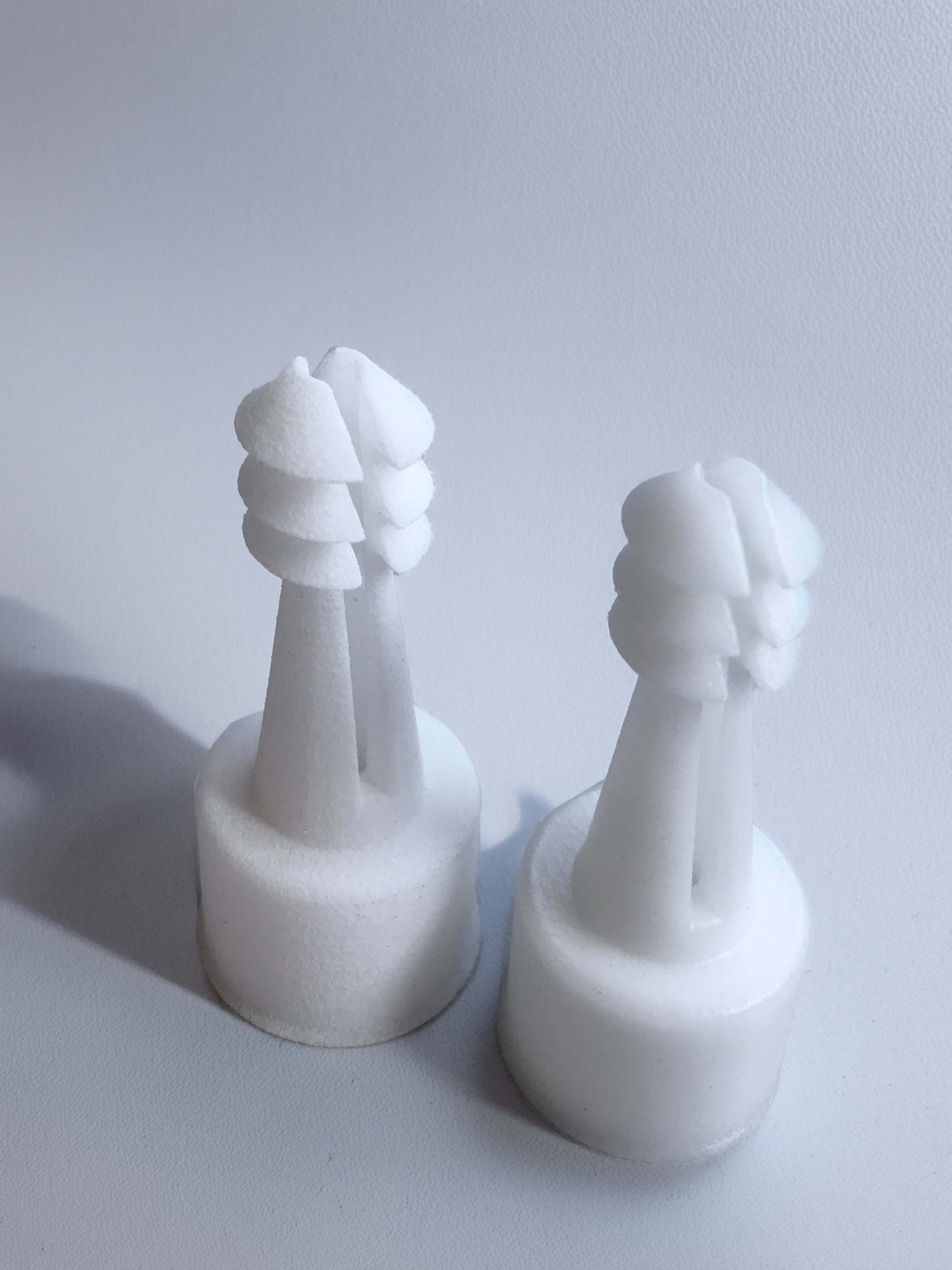 zwei weiße Kunststoffbauteile in Form von Schachfiguren stehen nebeneinander