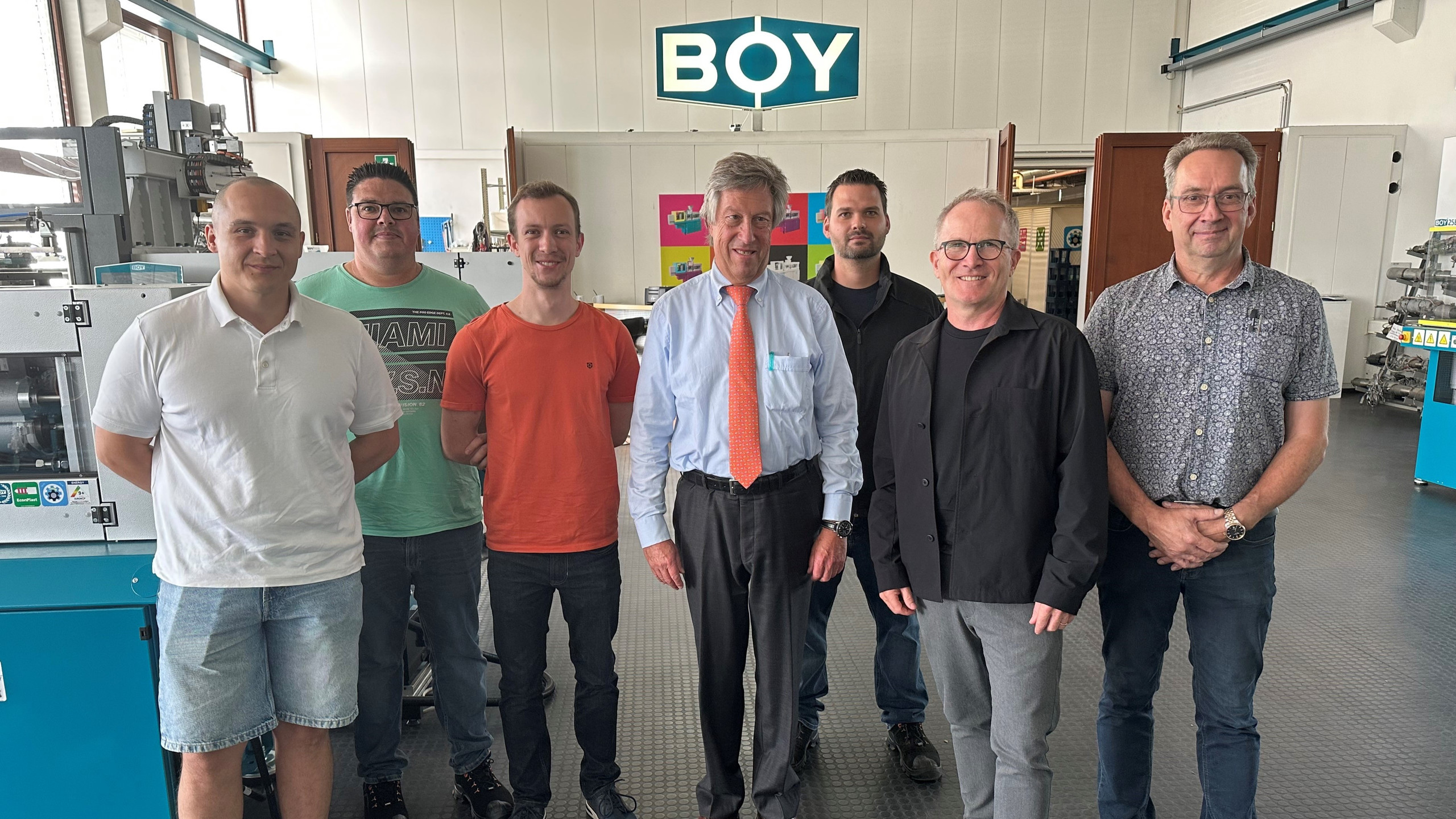 2 Männer bedienen ein Display einer Maschine, sie stehen mit dem Rücken zum Leser