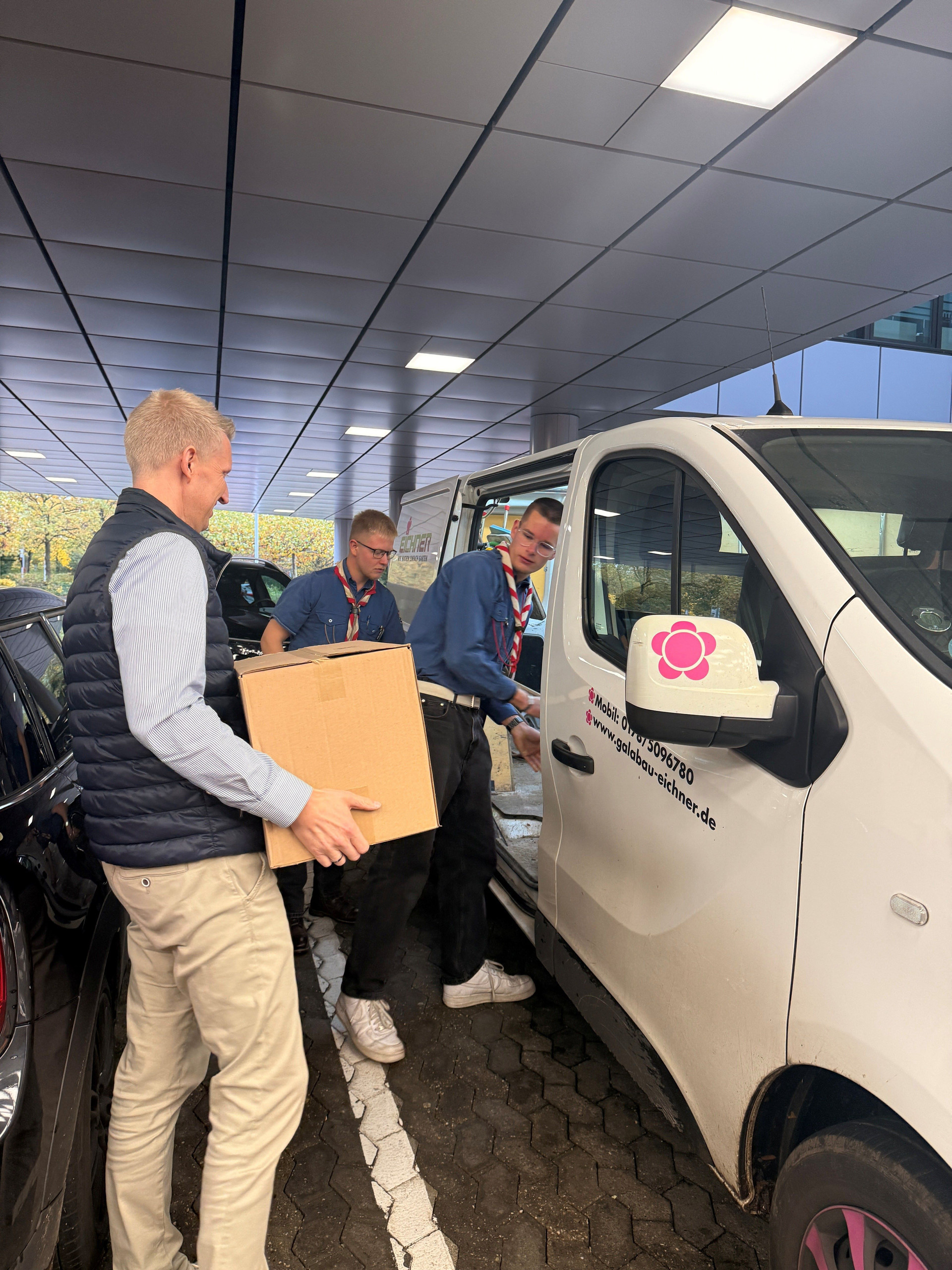 Thomas Franken von der Messe Düsseldorf übergibt Mehrwegbecher und hilft beim Verladen für die Lieferung an die örtliche Pfadfindergruppe.