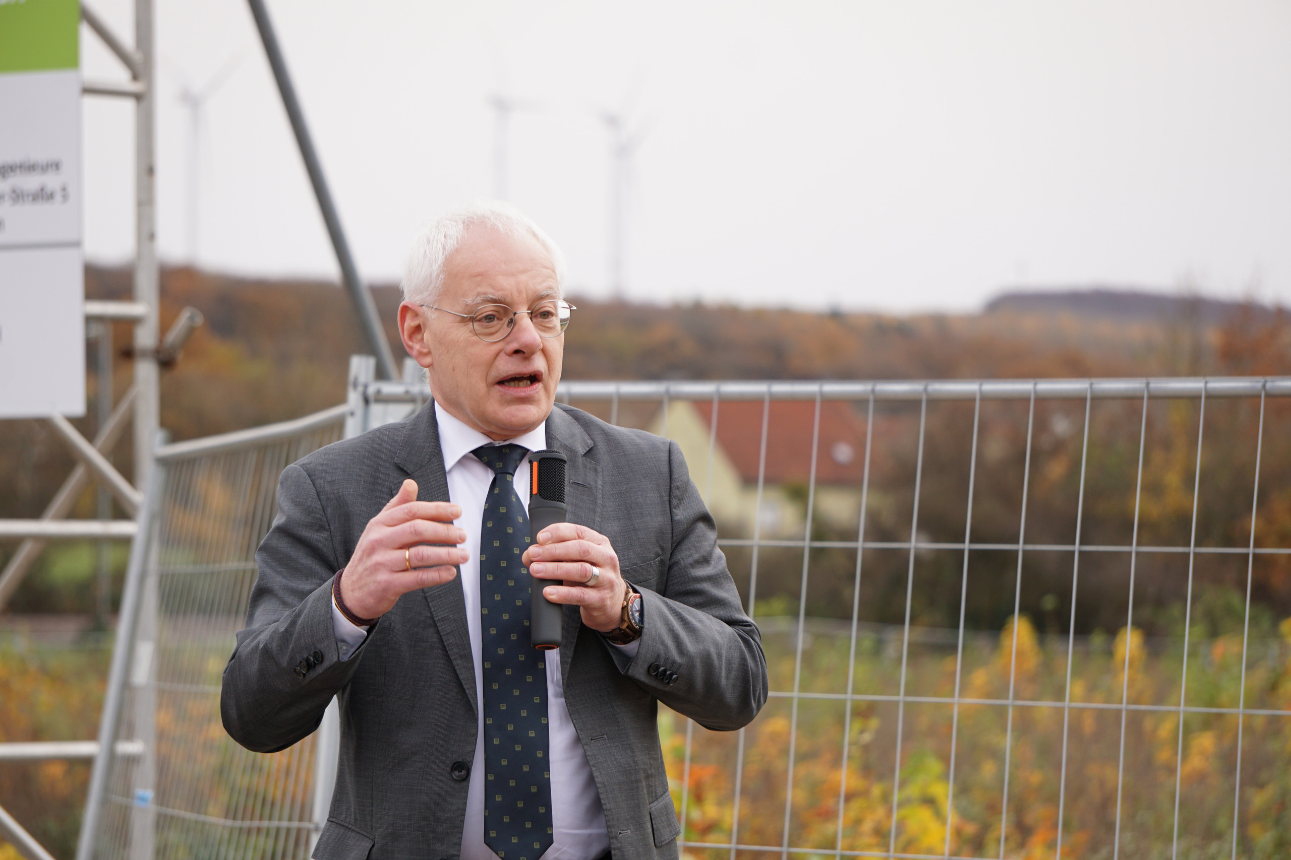 älterer Mann spricht auf einer Baustelle zu den Gästen