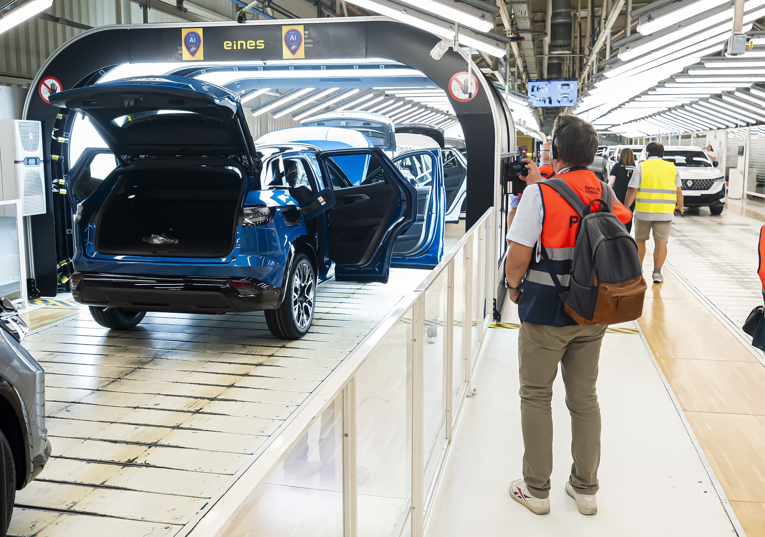 montierte Autos fahren in einen Lichttunnel, daneben ein Mensch der zuschaut