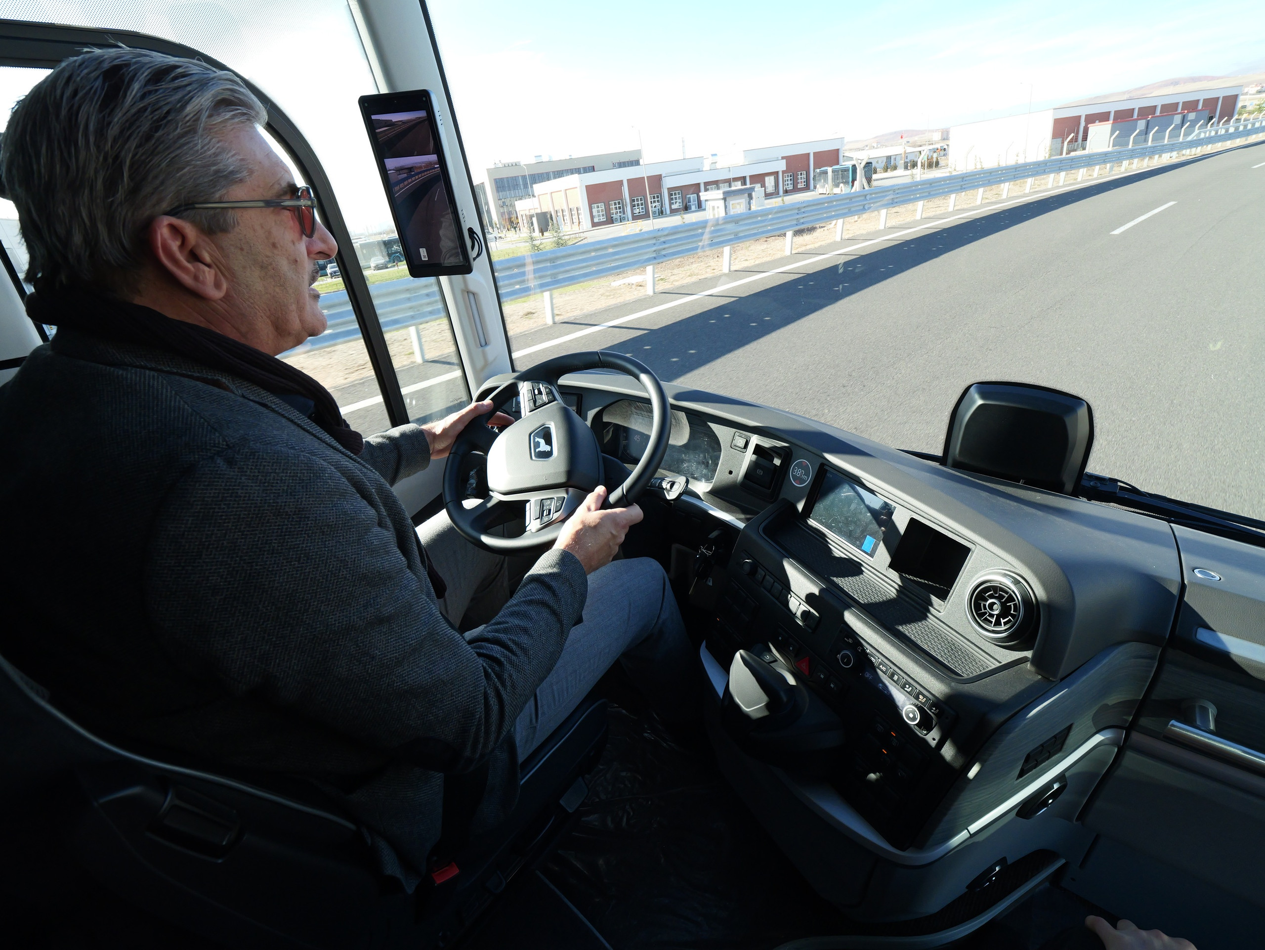 ein Fahrer fährt einen Reisebus auf einer Straße, Blick auf den Fahrer und durch die Windschutzscheibe
